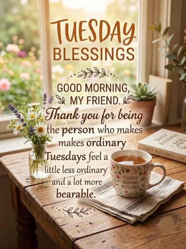 Warm morning light filtering through a window onto a wooden table with a steaming mug of tea, fresh flowers in a glass vase, and a rustic "Tuesday Blessings" message for friends and family.